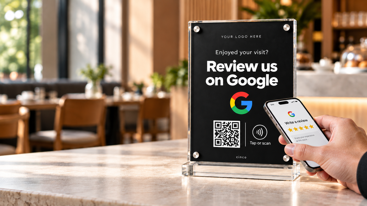 Phone showing a five-star review page beside a black CINCO Google Review stand